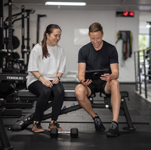 Ross reviewing a training plan with a client on a tablet